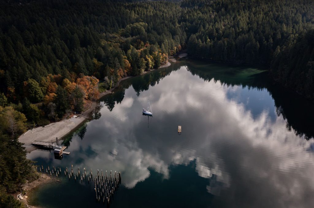 Sail boat anchored on a lake in forest photo taken from the sky